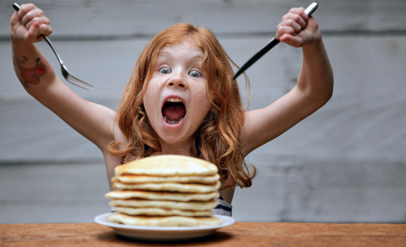 A girl eating a pile of pancakes